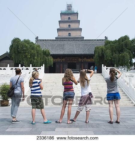 Stock Photograph - A Woman And Four Girls Standing In A Row Taking Pictures Of The Giant Wild Goose Pagoda; Xi'an, Shaanxi, China. Fotosearch