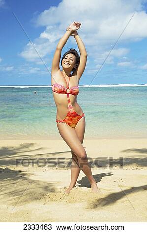 Stock Image - A woman at the beach in a unique bathing suit; Kauai, Hawaii, United States of America. Fotosearch