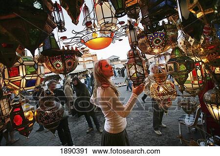 Stock Image - A Woman Browsing For Moroccan Lanterns In A Market Stall In The Souk.. Fotosearch