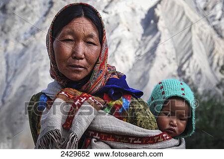 A woman carrying a young child on her back; Spiti Valley, India View Large Photo Image Stock Image - A woman carrying a young child on her back; Spiti Valley, India. Fotosearch