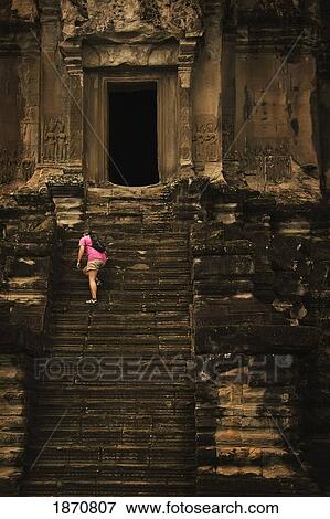 Stock Photo - A Woman Climbing Up The Steps Of A Old Building. Fotosearch