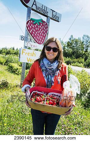 Stock Photography - A woman holds a basket full of fresh picked strawberries; Newfoundland and Labrador, Canada. Fotosearch