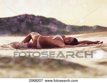 Stock Photo - A Woman In A Bikini Lays On The Wet Sand; Tarifa Cadiz Andalusia Spain. Fotosearch