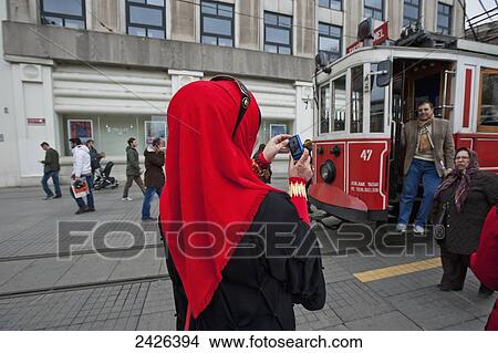 Picture - A woman in a headscarf takes a picture of a man on a tram; Istanbul, Turkey. Fotosearch