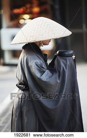 Stock Image - A Woman In A Robe And Conical Hat On Teapot Lane; Kyoto, Japan. Fotosearch