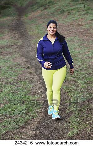 Stock Photograph - A woman in workout clothing walking down a path; San Francisco, California, USA. Fotosearch