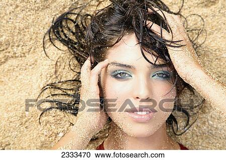 A woman laying in the sand with a sandy face, hair and arms; Kauai, Hawaii, United States of America View Large Photo Image Stock Image - A woman laying in the sand with a sandy face, hair and arms; Kauai, Hawaii, United States of America. Fotosearch