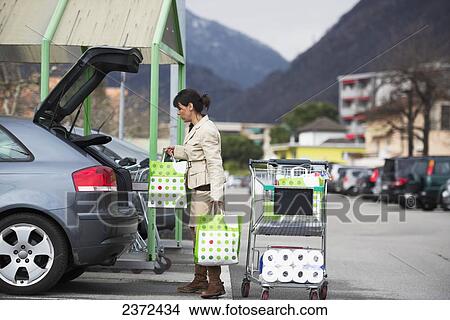 A Woman Loads Her Car With Shopping Bags In A Parking Lot; Ascona, Ticino, Switzerland View Large Photo Image Picture - A Woman Loads Her Car With Shopping Bags In A Parking Lot; Ascona, Ticino, Switzerland. Fotosearch