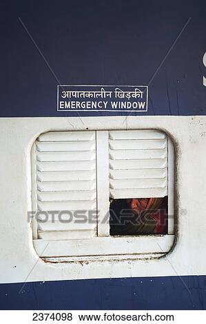 Stock Photo - A woman looks out the emergency window of a train; India. Fotosearch