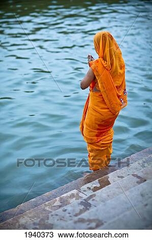 A Woman Offers Prayers On The Edge Of The Ganges River In The Ancient City Of Varanasi; Varanasi India View Large Photo Image Stock Image - A Woman Offers Prayers On The Edge Of The Ganges River In The Ancient City Of Varanasi; Varanasi India. Fotosearch