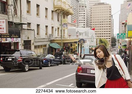 A woman on the side of the road hailing a cab; san francisco california united states of america View Large Photo Image Picture - A woman on the side of the road hailing a cab; san francisco california united states of america. Fotosearch