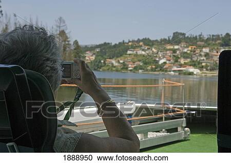 Stock Image - A Woman Passenger River Cruise Takes A Photograph Of The Scenery. Fotosearch