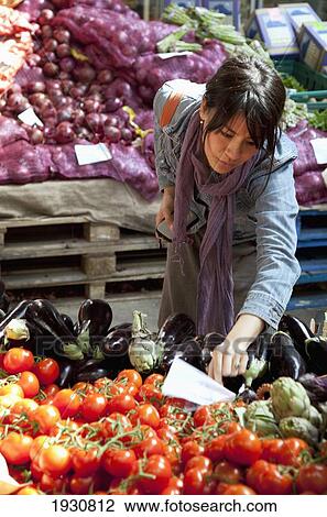 Stock Image - A woman picks fresh produce in a market; London, England. Fotosearch