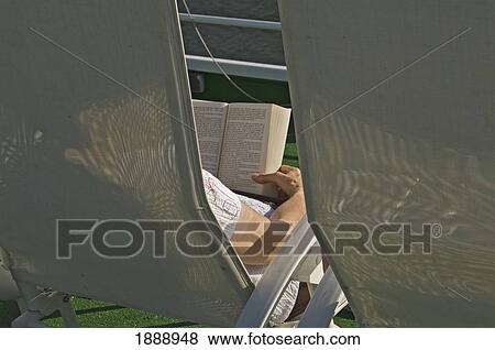 Stock Photo - A Woman Relaxing In A Chair Reading A Book Onboard A River Cruise. Fotosearch