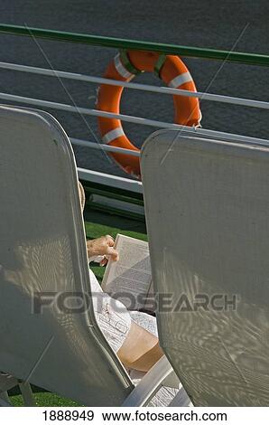 Stock Photo - A Woman Relaxing In A Chair Reading A Book Onboard A River Cruise. Fotosearch