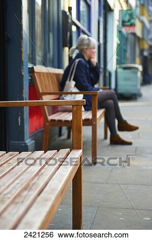 A woman sits on a bench in front of a building, Shoreditch; London, England View Large Photo Image Stock Photograph - A woman sits on a bench in front of a building, Shoreditch; London, England. Fotosearch