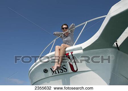 Stock Image - A Woman Sits On The Bow Of A Boat; Utila Island, Honduras. Fotosearch