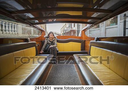 A woman sits on the seat of a boat taxi; Venice, Italy View Large Photo Image Stock Image - A woman sits on the seat of a boat taxi; Venice, Italy. Fotosearch