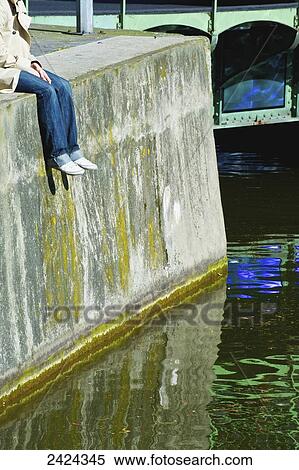 Stock Photography - A woman sits on the wall of the Canal Saint Martin; Paris, France. Fotosearch