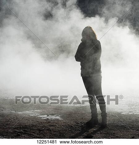 Stock Image - A woman stands in the steam of a geyser, El Tatio Geysers; Calama, Antofagasta Region, Chile. Fotosearch