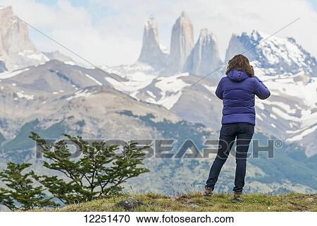 A woman stands with a view of the rugged mountain landscape, Torres del Paine National Park; Torres del Paine, Magallanes and Antartica Chilena Region, Chile View Large Photo Image Stock Image - A woman stands with a view of the rugged mountain landscape, Torres del Paine National Park; Torres del Paine, Magallanes and Antartica Chilena Region, Chile. Fotosearch