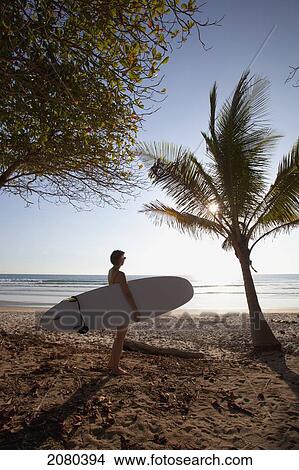 Picture - A Woman Surfer Holds Her Surfboard On Playa Santa Teresa (Santa Teresa Beach) In Santa Teresa And Mal Pais (Malpais) On The Nicoya Peninsula; Puntarenas Province, Costa Rica. Fotosearch