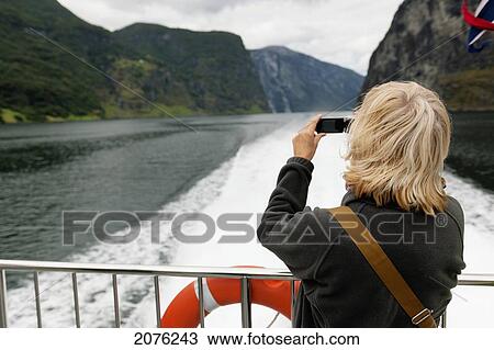 A Woman Takes A Picture With Her Camera From The Back Of A Boat; Sognefjord Norway View Large Photo Image Stock Image - A Woman Takes A Picture With Her Camera From The Back Of A Boat; Sognefjord Norway. Fotosearch