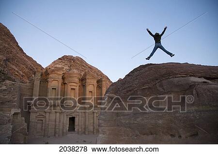 Stock Photo - A Woman Tourist Jumps Into The Air In Front Of The Nabatean Ruins Of The Monastery; Petra Jordan. Fotosearch