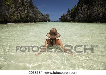 A Woman Tourist Wearing A Sun Hat And Bikini Relaxes In The Clear Waters Of Matinloc Island Near El Nido And Corong Corong; Bacuit Archipelago Palawan Philippines View Large Photo Image Picture - A Woman Tourist Wearing A Sun Hat And Bikini Relaxes In The Clear Waters Of Matinloc Island Near El Nido And Corong Corong; Bacuit Archipelago Palawan Philippines. Fotosearch