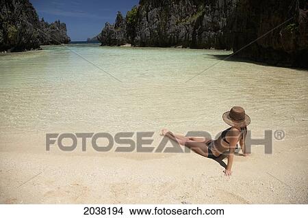 Picture - A Woman Tourist Wearing A Sun Hat And Bikini Relaxes In The Clear Waters Of Matinloc Island Near El Nido And Corong Corong; Bacuit Archipelago Palawan Philippines. Fotosearch