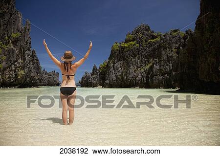 A Woman Tourist Wearing A Sun Hat And Bikini Stands With Arms Raised In The Clear Waters Of Matinloc Island Near El Nido And Corong Corong; Bacuit Archipelago; Palawan Philippines View Large Photo Image Stock Image - A Woman Tourist Wearing A Sun Hat And Bikini Stands With Arms Raised In The Clear Waters Of Matinloc Island Near El Nido And Corong Corong; Bacuit Archipelago; Palawan Philippines. Fotosearch