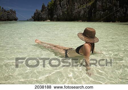 Stock Photo - A Woman Tourist Wearing A Sun Hat And Bikini Relaxes In The Clear Waters Of Matinloc Island Near El Nido And Corong Corong; Bacuit Archipelago; Palawan Philippines. Fotosearch