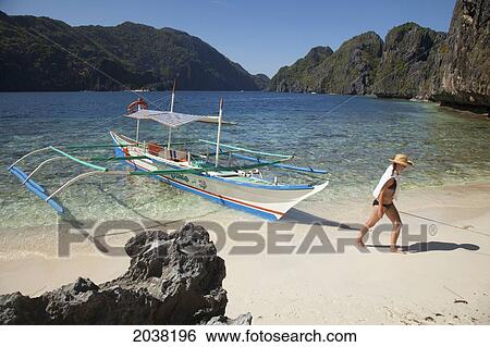 A Woman Tourist Wearing A Sun Hat And Bikini Walks Past A Bangka Boat Of Matinloc Island Near El Nido And Corong Corong; Bacuit Archipelago Palawan Philippines View Large Photo Image Stock Photograph - A Woman Tourist Wearing A Sun Hat And Bikini Walks Past A Bangka Boat Of Matinloc Island Near El Nido And Corong Corong; Bacuit Archipelago Palawan Philippines. Fotosearch