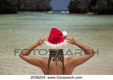Picture - A Woman Tourist Wears A Santa Hat And Bikini On Tropical Matinloc Island Near El Nido And Corong Corong; Bacuit Archipelago On Palawan Philippines. Fotosearch