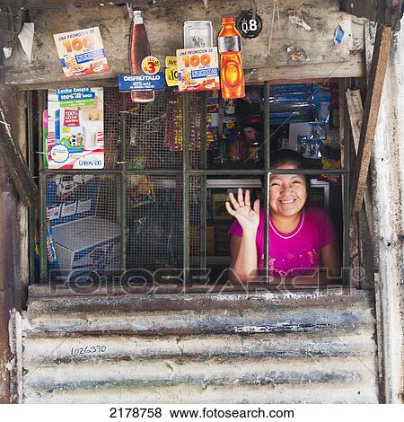 Stock Photo - A Woman Vendor Waving Through Her Open Shop Window; Guatemala City Guatemala. Fotosearch