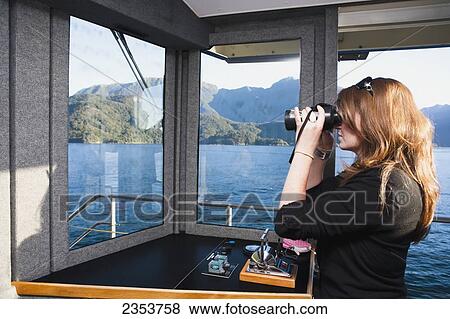 Stock Photo - A Woman Views The Fiords Through Binoculars On The Real Journey Boat To Doubtful Sound; New Zealand. Fotosearch