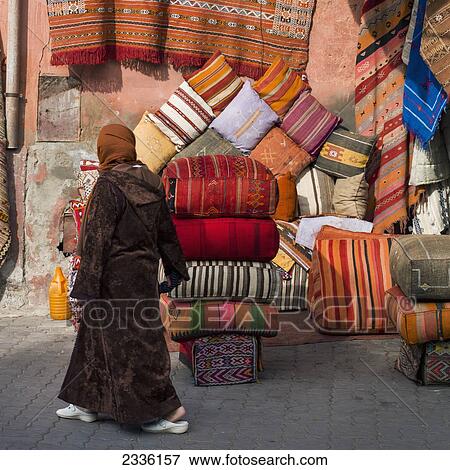 Stock Photo - A Woman Walks Past Colourful Cushions And Textiles On Display; Marrakesh, Marrakech-Tensift-El Haouz, Morocco. Fotosearch