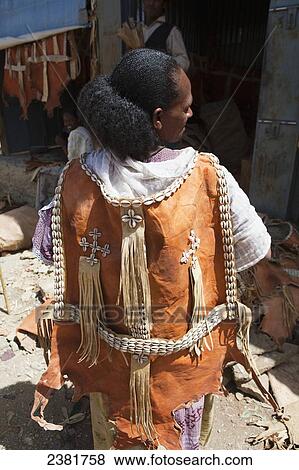 Stock Photo - A woman wearing a leather cape decorated with ornate cowrie shells; Tigray region, Ethiopia. Fotosearch