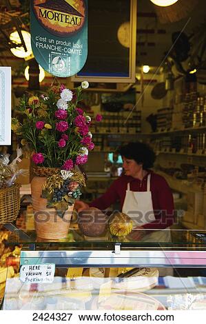 Stock Photo - A woman working behind the counter of a shop; Paris, France. Fotosearch