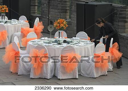 Stock Image - A Worker Sets Up A Formal Table For A Wedding Celebration; Beijing, China. Fotosearch
