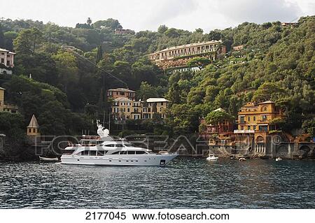 Stock Photography - A Yacht Mooring In The Water With Residential Buildings Along The Water's Edge; Italy. Fotosearch