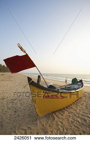 Stock Image - A yellow boat on the Neeleshwar hermitage hotel beach; Kerala, India. Fotosearch