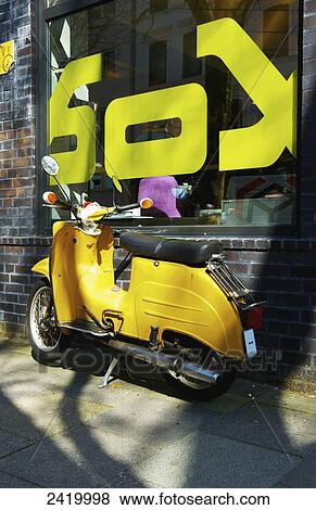 A yellow motorcycle parked outside a building with a large window and decal sign; Hamburg, Germany View Large Photo Image Stock Photo - A yellow motorcycle parked outside a building with a large window and decal sign; Hamburg, Germany. Fotosearch