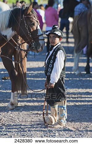 A young boy dressed in traditional costume stands by a horse; Malargue, Argentina View Large Photo Image Stock Image - A young boy dressed in traditional costume stands by a horse; Malargue, Argentina. Fotosearch