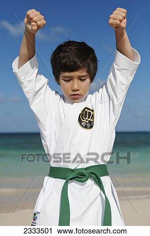 Stock Image - A young boy in a martial arts uniform on a beach; Honolulu, Oahu, Hawaii, United States of America. Fotosearch