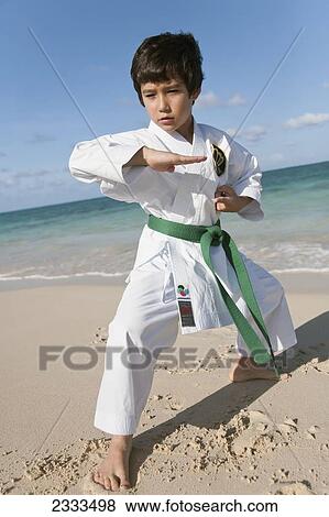Stock Photo - A young boy in a martial arts uniform on a beach; Honolulu, Oahu, Hawaii, United States of America. Fotosearch
