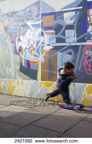 A young boy rides his scooter on a sidewalk past a wall full of graffiti, Portobello Road; London, England View Large Photo Image Stock Image - A young boy rides his scooter on a sidewalk past a wall full of graffiti, Portobello Road; London, England. Fotosearch
