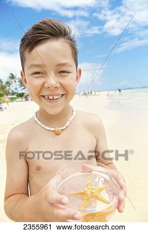 A young boy standing on the beach holding a bowl with a starfish in it; Kailua, Hawaii, United States of America View Large Photo Image Stock Image - A young boy standing on the beach holding a bowl with a starfish in it; Kailua, Hawaii, United States of America. Fotosearch