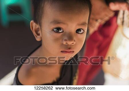 Stock Image - A young child looking into the camera in Old Market; Battambang, Cambodia. Fotosearch