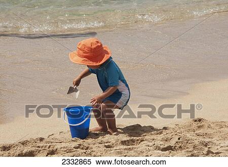 Stock Photography - A Young Child Playing In The Sand On Waikiki Beach; Oahu, Hawaii, United States Of America. Fotosearch